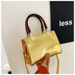 Detail of metallic gold crocodile embossed handbag with resin handle and shoulder strap
