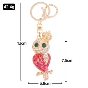 Sparkling rhinestone owl keychain with gold crown and emerald eyes on white background