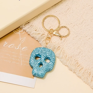 Vue détaillée du porte-clés tête de mort avec strass bleus et fermoir doré en métal
