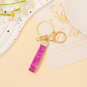 Dettaglio del portachiavi in pelle con strass rosa e chiusura dorata su vassoio decorativo