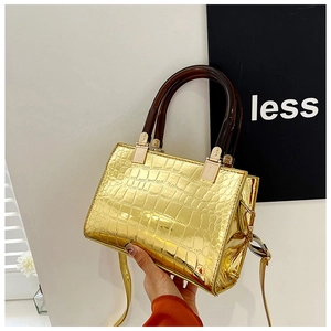 Detail shot of golden crocodile pattern glossy handbag with translucent handles