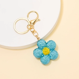 Détail macro du porte-clés fleur bleu clair avec strass brillants et fermoir doré