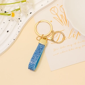Dettaglio del portachiavi in pelle con strass blu e moschettone dorato su base decorata