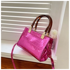 Detail of fuchsia crocodile texture bag with amber resin handles and gold hardware