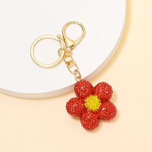 Détail d'un porte-clés fleur rouge avec strass brillants et fermoir en métal doré