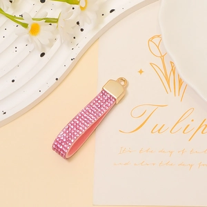 Detail of pink rhinestone leather strap with golden ring on a decorative white tray