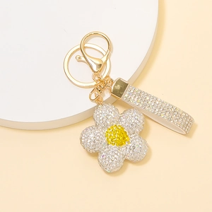 Détail d'un porte-clés fleur dorée orné de strass brillants avec un fermoir mousqueton