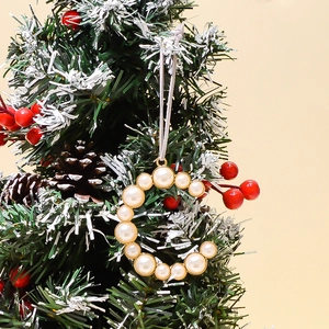 Close-up of a pearl alphabet ring pendant hanging on a festive decorated Christmas tree