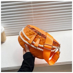 Détail du sac banane matelassé orange avec des chaînes de perles élégantes