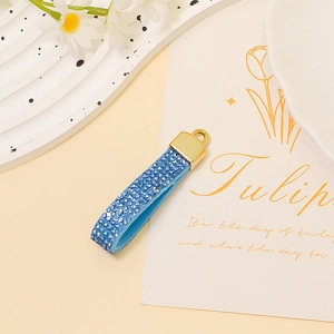 Close-up of blue rhinestone ribbon keychain with a polished gold alloy ring detail