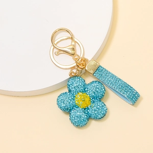 Vue détaillée du porte-clés fleur en strass bleu clair avec fermoir doré et sangle brillante