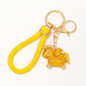 Close-up of yellow braided leather strap and golden horse pendant with metal ring keychain