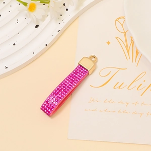 Detailed view of pink rhinestone strap keychain with golden hook and elegant metal finish