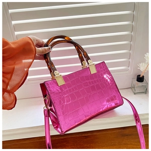 Detail of fuchsia crocodile embossed tote bag with tortoise shell handles and gold hardware
