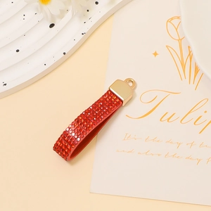 Close-up of red rhinestone encrusted U-shaped pendant charm with gold metal clasp