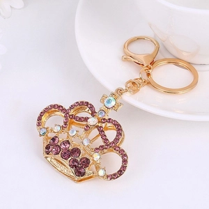 Detailed close-up of a golden crown keychain featuring purple and iridescent rhinestones