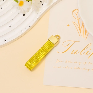 Macro detail of golden rectangular pendant with textured rhinestone inlay and tulip card