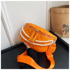 Détail du sac ceinture orange matelassé avec chaînes de perles et large bandoulière
