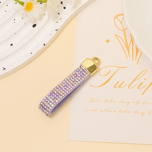Detail of purple rhinestone tassel keychain with golden metal ring and leather texture