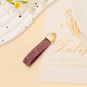 Close-up of purple rhinestones on a heart-shaped keychain with gold metal buckle