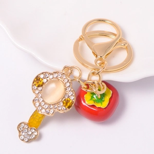 Detailed macro view of golden Persimmon keychain with sparkling rhinestones and red enamel