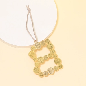 Macro view of gold-tone alloy letter B pendant with textured hollow striped pattern