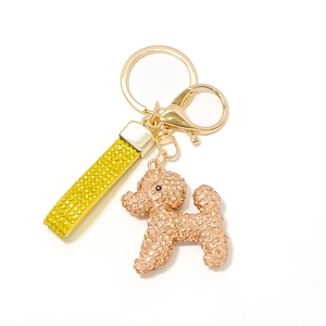 Détail d'un porte-clés chiot en strass doré rose avec lanière en cuir jaune et fermoir