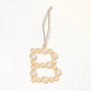Detailed view of the letter B keychain with inlaid pearls and golden metal frame