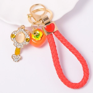 Detailed view of rhinestone persimmon keychain with red leather braided strap