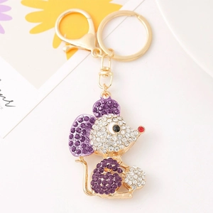 Dettaglio macro del portachiavi a topo dorato con strass viola e pallina di cristallo