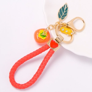 Detail of red woven leather keychain with rhinestone peanut and persimmon pendants