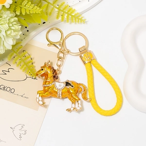 Dettaglio del portachiavi a forma di cavallo dorato con smalto e cordino giallo