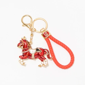Dettaglio portachiavi cavallo in smalto rosso con strass e cinturino in pelle intrecciata