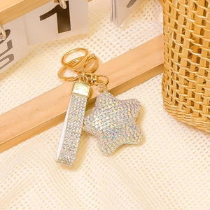 Pentagram star keychain with iridescent rhinestones and golden hardware on wooden display