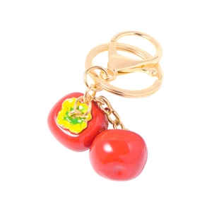 Close-up of golden metal key ring with double red persimmon charms and rhinestone detail