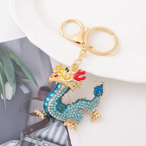Detailed close-up of a gold-toned dragon keychain with vibrant blue sparkling rhinestones