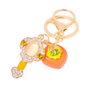 Golden crystal key ring with diamond-studded key and orange persimmon fruit pendant