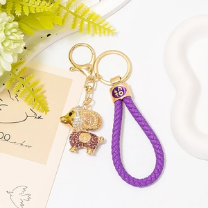 Détail d'un porte-clés mouton doré avec strass et cordon tressé violet élégant