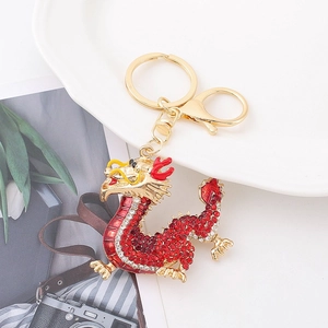Detail of a golden dragon keychain with red rhinestones on a white porcelain plate