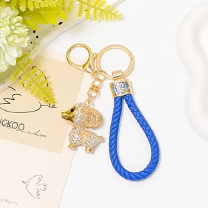 Détail d'un porte-clés mouton doré avec strass blancs et cordon en cuir bleu tressé