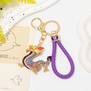 Detail of a Chinese zodiac dragon keychain with rhinestones and purple woven leather rope