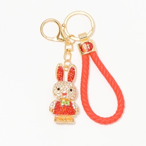 Macro detail of a rhinestone rabbit keychain with red braided cord and gold-plated hardware