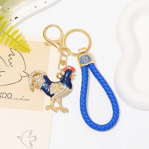Dettaglio portachiavi gallo in smalto blu con strass e ciondolo moneta d'oro fortuna