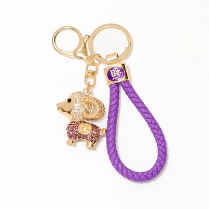 Détail du porte-clés mouton violet avec strass brillants et lanière en cuir tressé