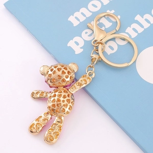 Détail d'un porte-clés ours doré avec motif cœur ajouré et strass violets étincelants