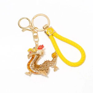 Detailed close-up of golden Chinese dragon keychain with rhinestones and woven leather strap