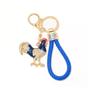 Dettaglio portachiavi a forma di gallo in smalto blu con strass e cinturino in pelle