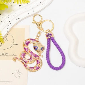 Détail du porte-clés serpent doré avec émail violet, strass et breloque porte-bonheur