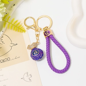 Detailed macro view of purple woven cord keychain with a blue rhinestone lucky bag pendant