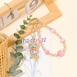 Detail view of a pink beaded cat charm with gold alloy rhinestones and purple gemstone